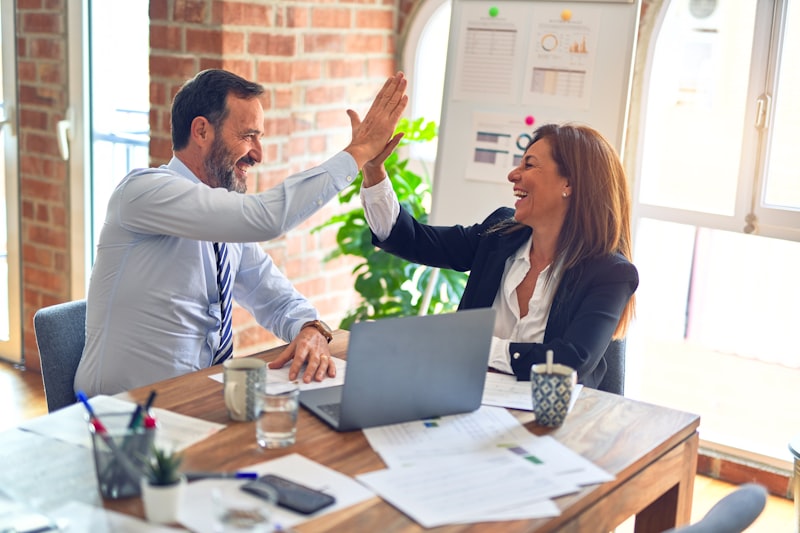Two Greenway Acquisitions professionals celebrating a sales win with a high five in the office